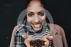 Portrait of african american laughing woman holding coffee beans