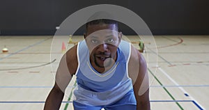 Portrait of african american male basketball player playing in indoor court, in slow motion