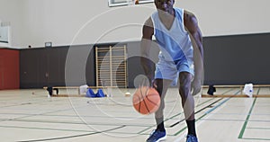 Portrait of african american male basketball player playing in indoor court, in slow motion
