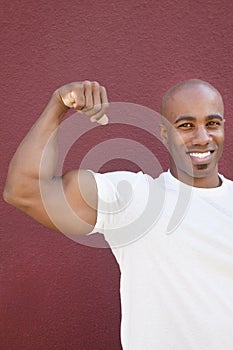 Portrait of an African American male flexing muscles over colored background