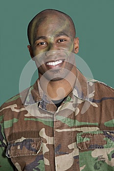 Portrait of an African American male US Marine Corps soldier with camouflaged face over green background photo