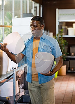 Portrait of african american man choosing pots for flowers and trees in market