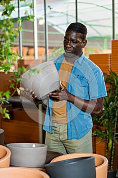 Portrait of african american man choosing pots for flowers and trees in market