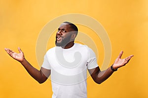 Portrait of african american man with hands raised in shock and disbelief. over yellow background.