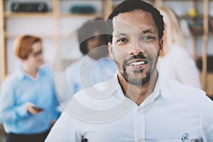 Portrait of african american man looking and smiling at the camera.Business team on a background in modern office