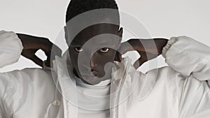 Portrait of African American man in white jacket wearing hood isolated on background. Cool guy