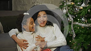 Portrait of African American mom and her little daughter with shocked and surprised wow face expression. Woman and girl