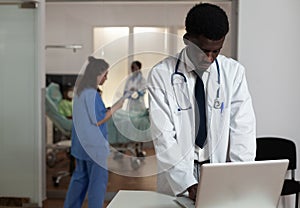 Portrait of african american physician doctor standing at desk in hospital ward