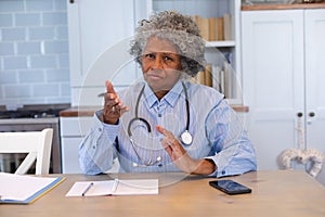 Portrait of african american senior female doctor talking looking at the camera at home