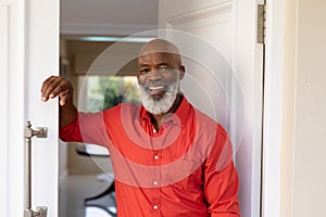 Portrait of african american senior man smiling while standing at front door of house