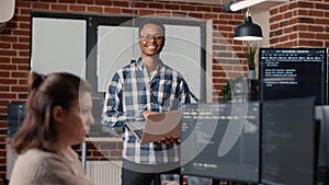 Portrait of african american software developer holding laptop looking up and smiling photo