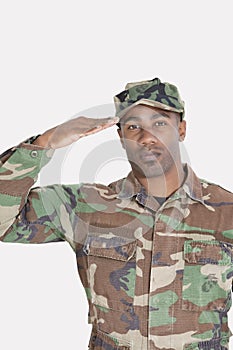 Portrait of an African American US Marine Corps soldier saluting over gray background