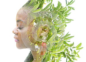 A portrait of an African American woman dissolving into fresh green leaves.