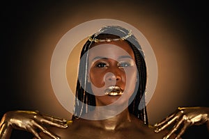 Portrait of an African-American woman with gold jewelry in her hair. The model's arms, neck and shoulders are