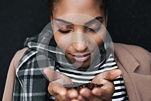 Portrait of african american woman holding coffee beans in her palms