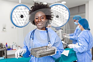 Portrait of African American woman surgeon standing in operating room, ready to work on a patient. Female medical worker in