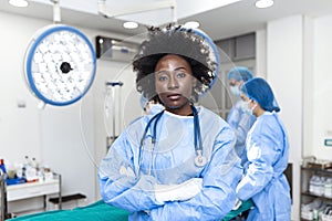 Portrait of African American woman surgeon standing in operating room, ready to work on a patient. Female medical worker in