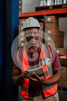 Portrait of African American worker standing holding digital tablet smiling in packaging factory.
