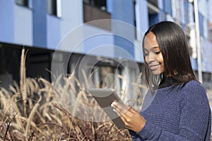 Portrait of African American young beautiful woman standing on the street while using a mobile phone