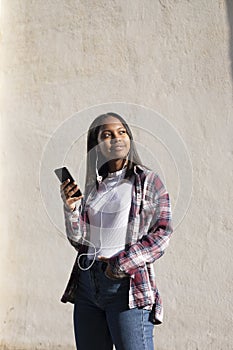 Portrait of African American young beautiful woman standing on the street while using a mobile phone