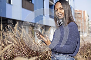 Portrait of African American young beautiful woman standing on the street while using a mobile phone