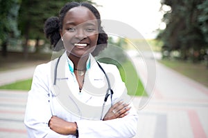 Portrait of an African American young girl. Doctor in a white coat, with a phonendoscope, smile, outdoors