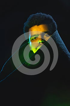 Portrait of African-American young man in black coat isolated on dark background