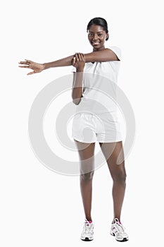 Portrait of an African American young woman stretching arm over white background