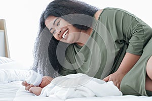 Portrait of African big mother feeding bottle of milk to cute infant at bedroom