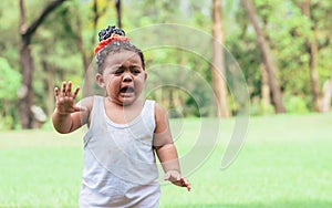 Portrait of African black adorable little girl crying with sadness while standing and playing in outdoor backyard, green field,