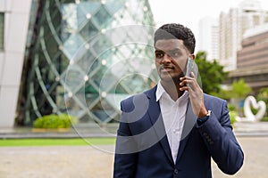Portrait of African businessman outdoors in city talking on mobile phone