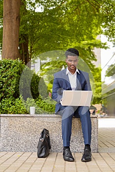 Portrait of African businessman using laptop computer outdoors in city