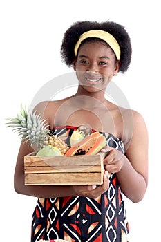 Portrait of African girl teen with curly hair wearing traditional clothes, holding tropical basket fruits. Happy smiling African