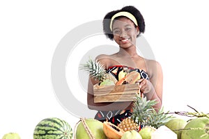 Portrait of African girl teen with curly hair wearing traditional clothes, holding tropical basket fruits. Happy smiling African