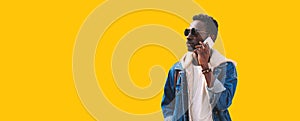 Portrait of african man talking on smartphone looking away isolated on yellow background, blank copy space for advertising text