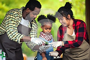 Portrait of African man and wife teaching the children to plant seedlings in greenhouse