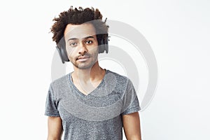 Portrait of african man in wireless headphones listening to streaming music service and enjoying the beat over white