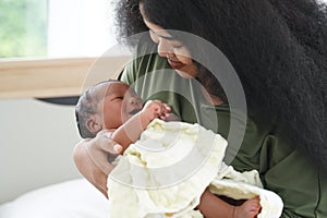 Portrait of African mom carrying adorable newborn baby in her arm. Happy lovely African American family mother and son