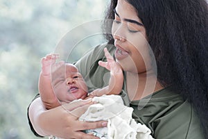 Portrait of African mom carrying adorable newborn baby in her arm. Happy lovely African American family mother and son