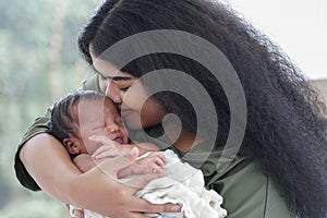 Portrait of African mom carrying and kiss adorable newborn baby in her arm. Happy lovely African American family mother and son