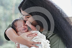 Portrait of African mom carrying and kiss adorable newborn baby in her arm. Happy lovely African American family mother and son