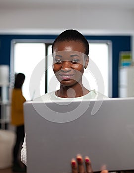 Portrait of african woman looking at camera smiling standing in start up multimedia design agency