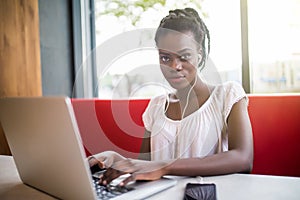 Portrait of smiling afro american female enjoying favourite playlist or listening audio language lessons in digital modern headpho