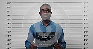 Portrait of afro american male person holding sign for photo in police department. Crop view of young man posing