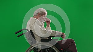 Portrait of aged disabled man on chroma key green screen. Close up senior man in wheelchair thinking deeply, upset