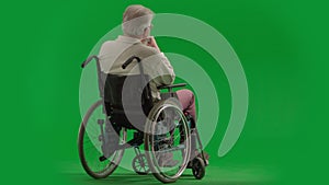 Portrait of aged disabled man on chroma key green screen. Full shot senior man sitting in wheelchair thinking deeply