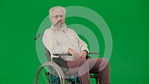 Portrait of aged man on chroma key green screen background. Senior man sitting in wheelchair looking directly at the