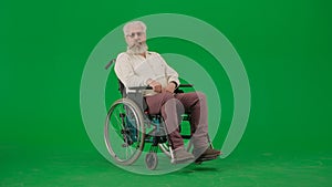 Portrait of aged man on chroma key green screen background. Senior man sitting in wheelchair looking directly at the