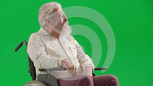 Portrait of aged man on chroma key green screen. Close up senior man sitting in wheelchair thinking, upset depressed