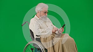 Portrait of aged man isolated on chroma key green screen background. Senior man in wheelchair covered by plaid swiping